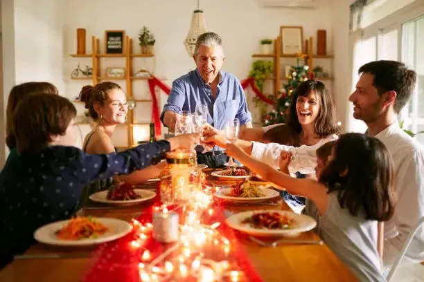 Familia brindando alrededor de la mesa en una cena de Navidad