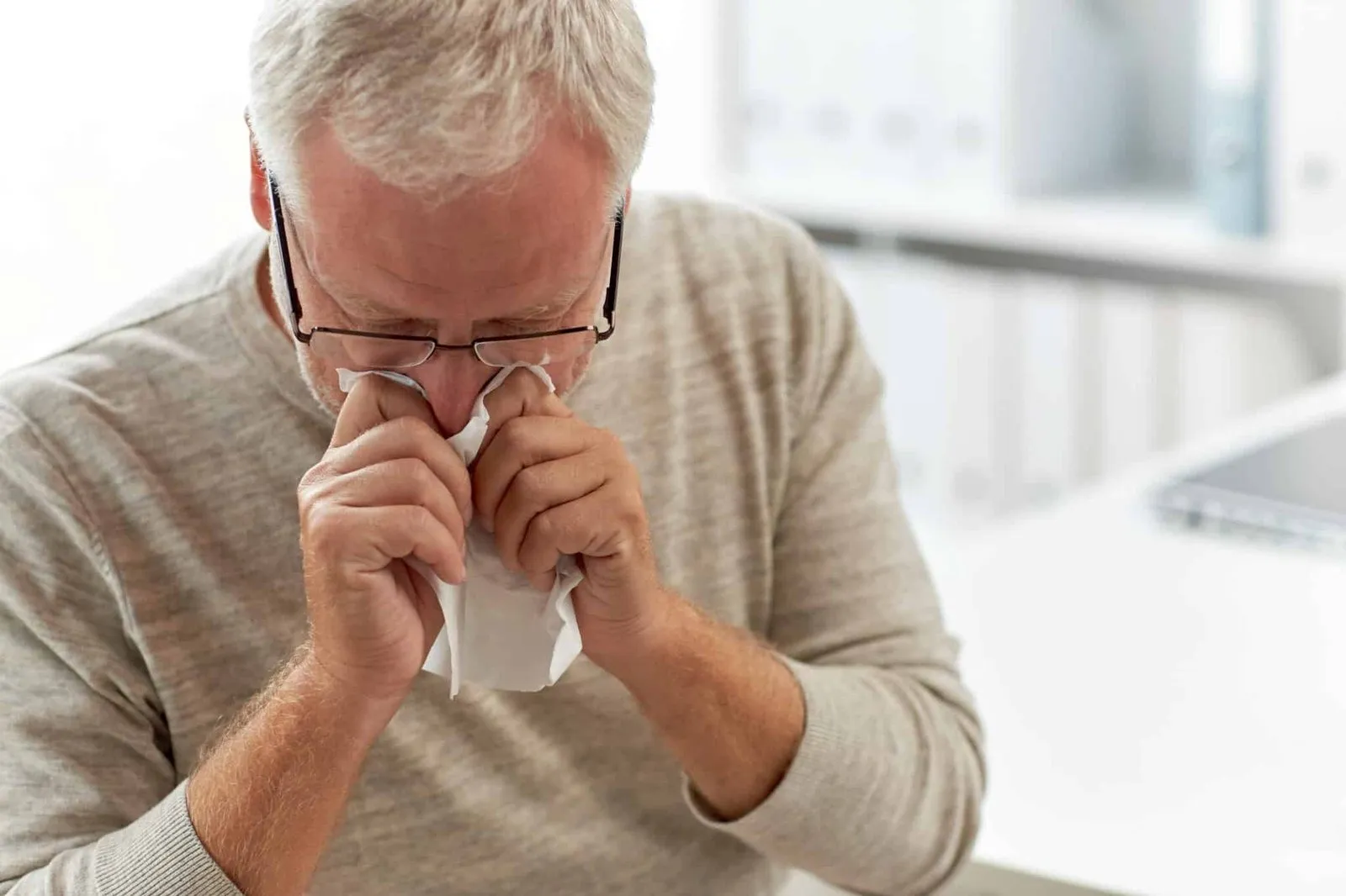Hombre mayor con alergia sonándose la nariz con un pañuelo