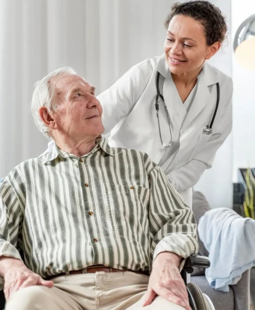 Profesional de la salud conversando con un adulto mayor en silla de ruedas