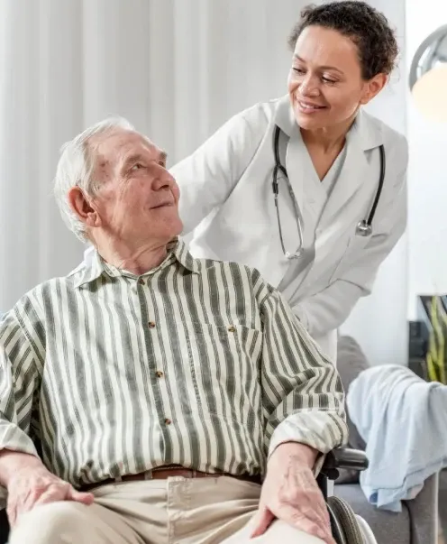 Profesional de la salud conversando con un adulto mayor en silla de ruedas